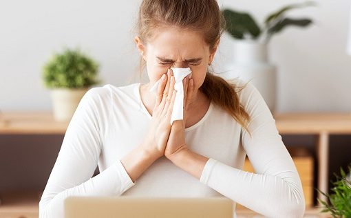 woman sneezing into tissue