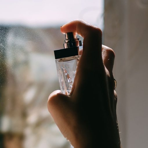 woman spraying perfume on neck