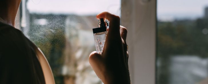 woman spraying perfume on neck