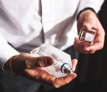 man in white dress shirt holding a bottle of men's cologne