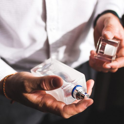 man in white dress shirt holding a bottle of men's cologne