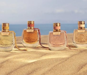 a line of 4 Chloe Nomade perfume bottles on a beach