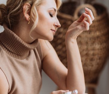 young woman enjoying the smell of perfume on her wrist