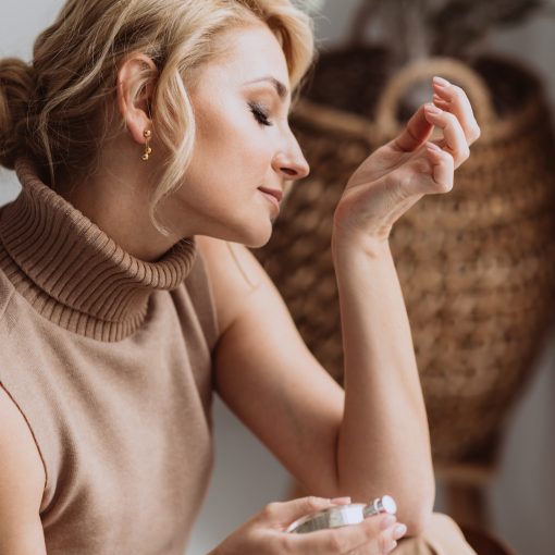 young woman enjoying the smell of perfume on her wrist