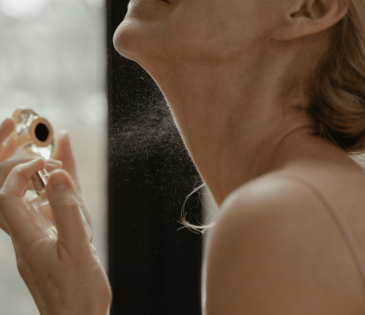 woman spraying perfume on neck