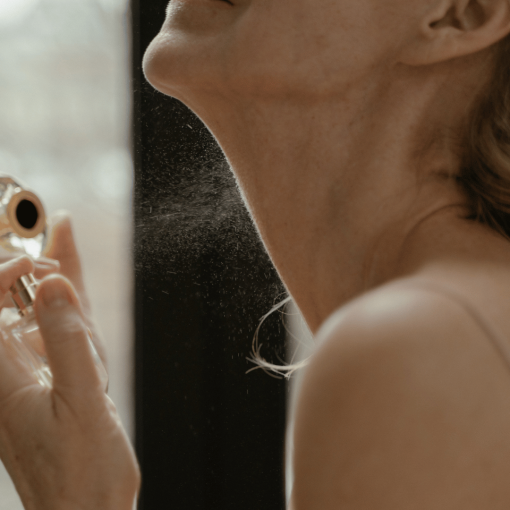 woman spraying perfume on neck