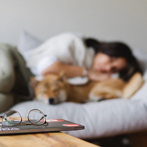 A lady with her pet dog lying on a couch