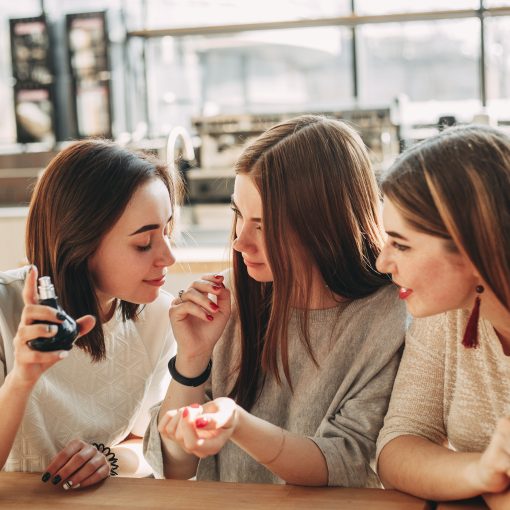 Three young women friends smelling new perfume
